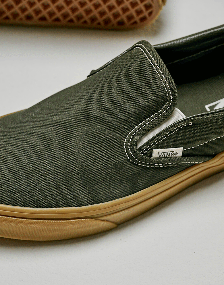 Close-up on the gum-colored sidewall on the Gum Obsidian Fern Green Classic Slip-On in a photography studio.