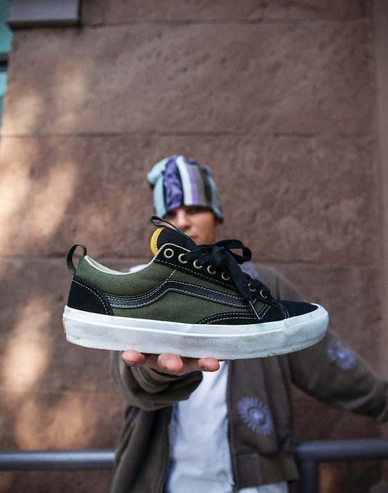 A close-up of black and green Skate Old Skool 36+ shoes with a black Sidestripe held by pro skater