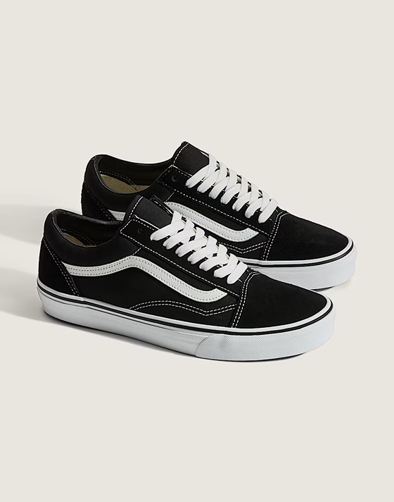Side view of a pair of black Old Skool shoes, styled against an off-white backdrop in a photography studio, showcasing their classic look in crisp detail.