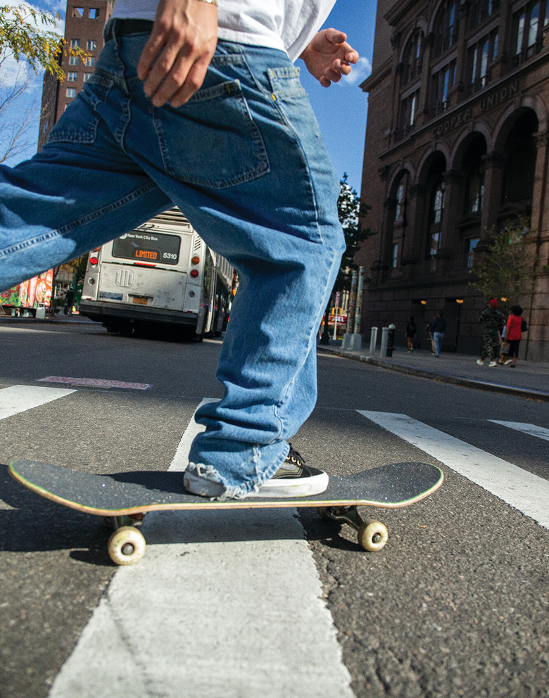 Skater Etienne Gagné is shown boardsliding on a curved rail. The image is blurred and shows multiple frames of Gagné during the grind.
