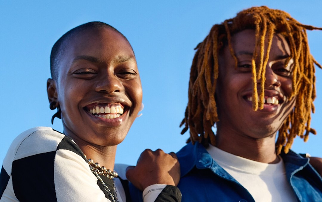 A close-up of two friends smiling in Vans clothes during golden hour.