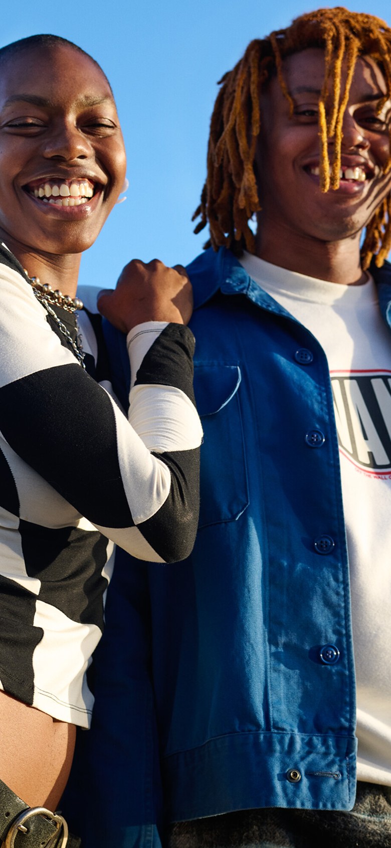 A close-up of two friends smiling in Vans clothes during golden hour.