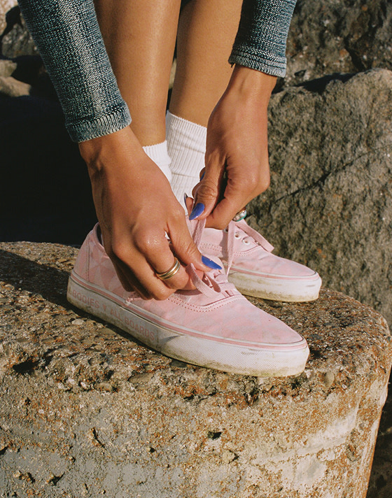 Someone ties their pink Authentic that say "All Bodies, All Boards" on the rubber sidewalls at the beach.