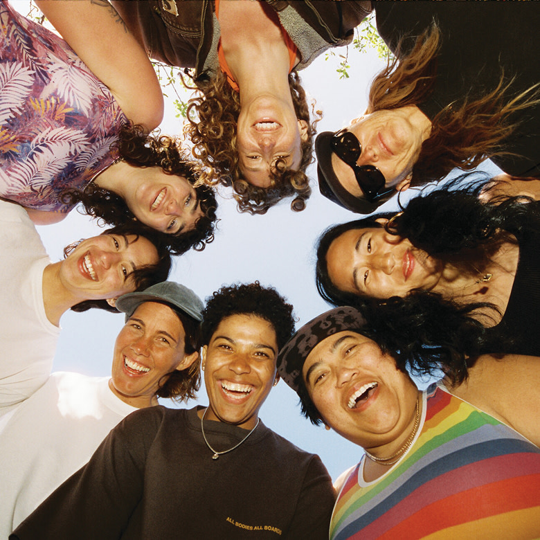 A group of friends smile looking down at the camera in a circle in Vans clothes.