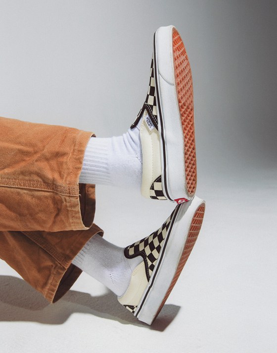 Close-up of a boy stacking his feet wearing black and white Checkerboard Slip-On.
