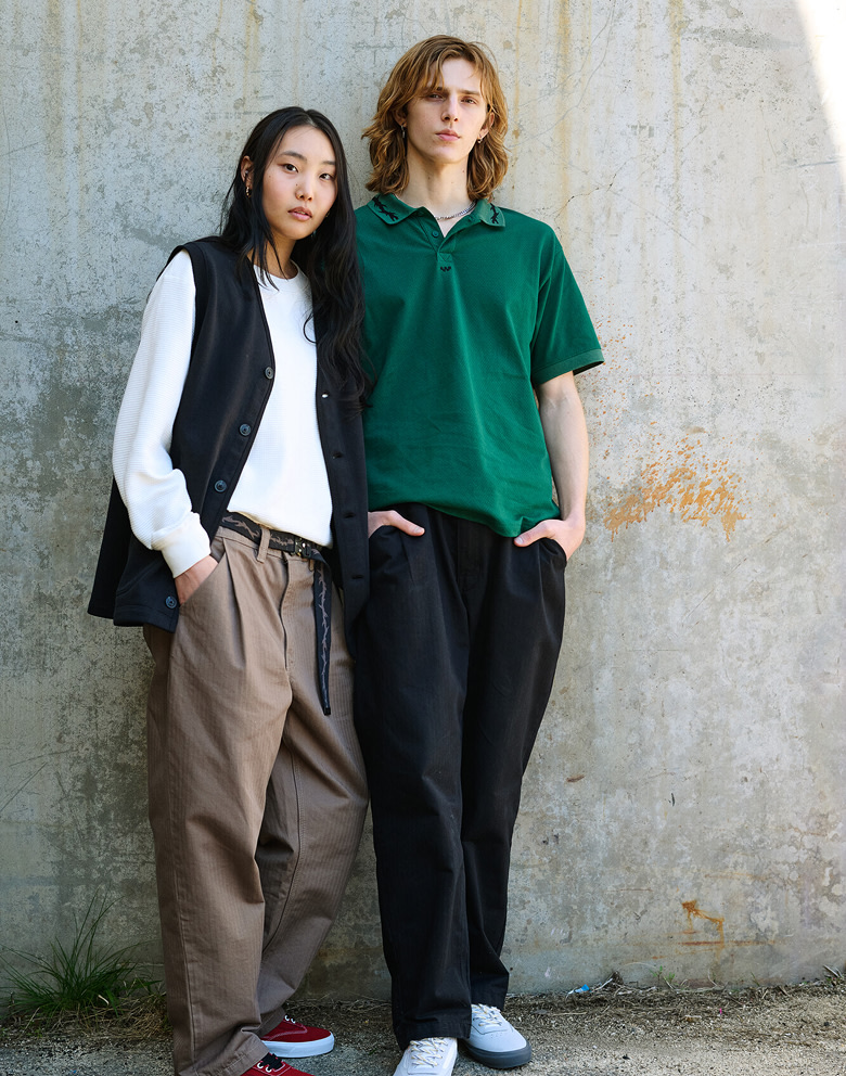 A man and woman pose in front a cracked concrete wall in Vans clothes.