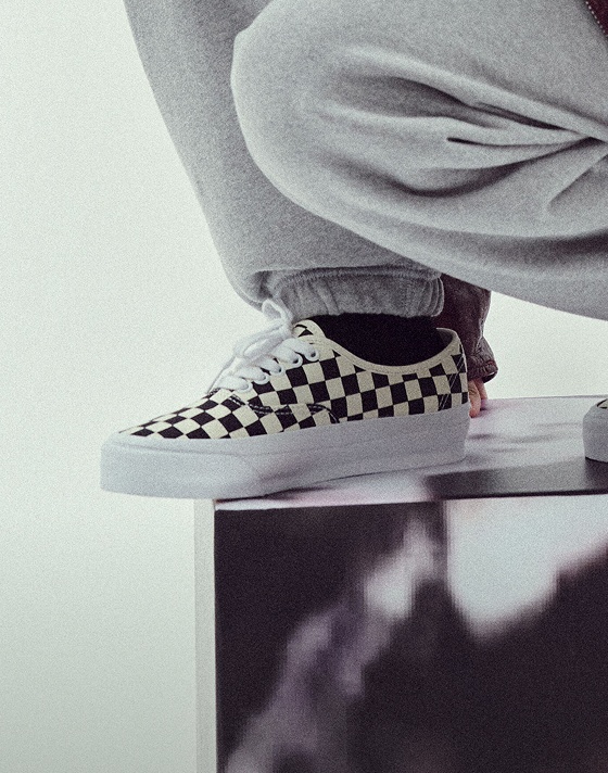 Someone bending down wearing checkerboard Authentic shoes.