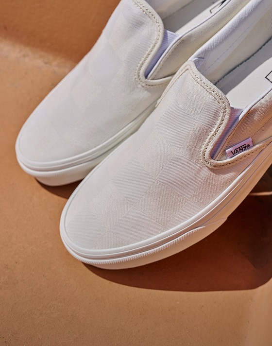 A closeup of the Vans Warm Beige Classic Slip-On on an orange bench.
