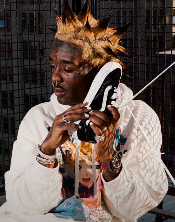 Lil Uzi Vert holding a black Old Skool shoe to his ear like a phone.