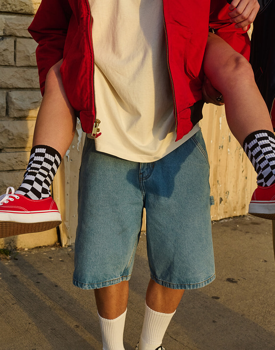 A chest-down shot of someone giving another person a piggyback ride wearing red Authentic shoes and Checkerboard quarter socks.
