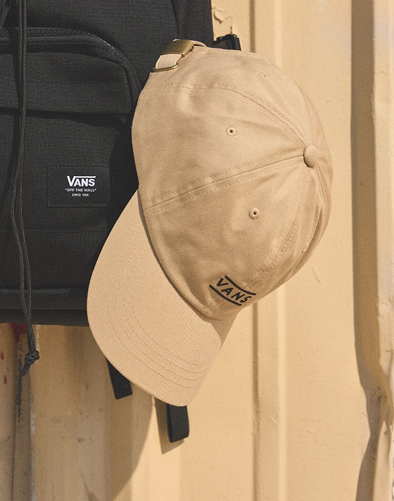 An Incense Brown Half Box Jockey Hat dangles from a black Vans Startle Backpack.