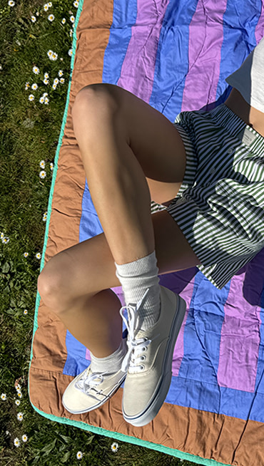 @yesconnieishere lays on a blanket on the grass wearing Off White Premium Authentic shoes.