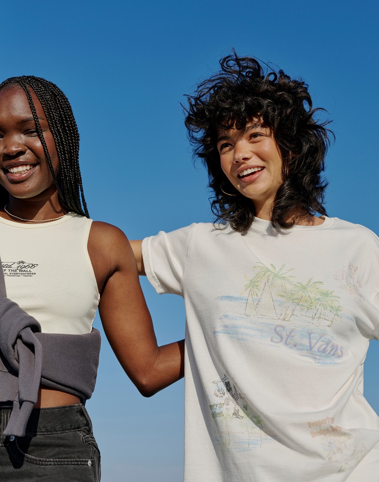 A young woman in a Vintage St. Vans shirt poses for the camera with her arms around a young woman wearing a Lemon Icing Yellow Everydayness Crop Tank Top.