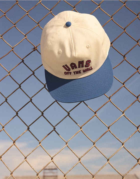 A Vans Design Co. Low Hat hangs on a cyclone fence.
