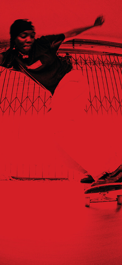 A skateboarder powerslides on the loading dock of a brick building with a vibrant red overlay on the image.