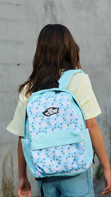 A close-up of a girl walking away from the camera wearing a crystal blue Kids Old Skool Grom Backpack.
