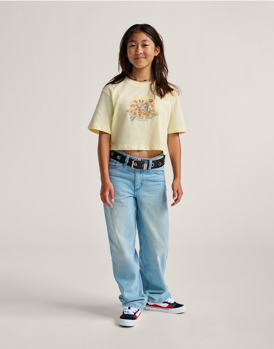 A young girl poses in a photography studio wearing Kids Sirelle Puddle Pants and a yellow Vans Off the Wall t-shirt.