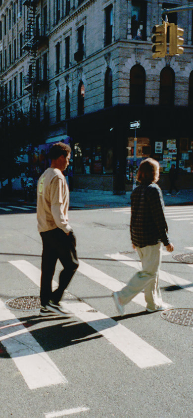 Three young men walk single file in a crosswalk in New York City wearing UltraRange 2.0 shoes.