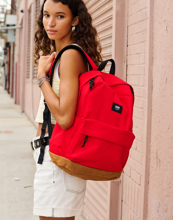 A young woman looks over her shoulder at the camera wearing the Everydayness Crop Tank Top and red Old Skool Sport Backpack.