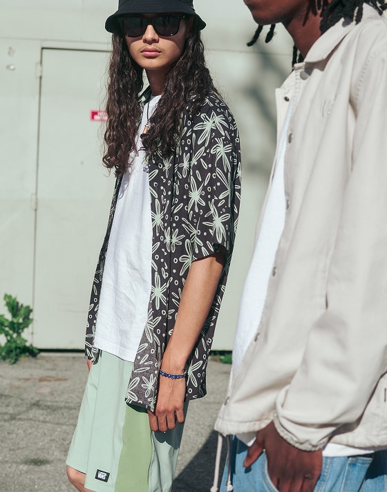 Two guys walk in the city on a sunny day, wearing relaxed Vans clothing styles.