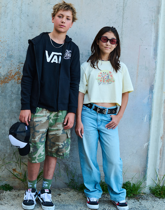 Young kids pose in front of a wall wearing Vans apparel and shoes.