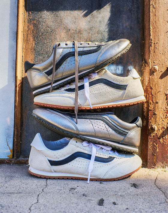 A styled stack of suede and shimmery Super Lowpro shoes stand out against a weathered exterior wall.