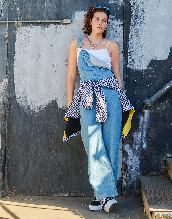 A young woman poses in a photography studio wearing the Everydayness Crop Tank Top, Jennifer 3'-inch Shortie, and red Old Skool Sport Backpack.