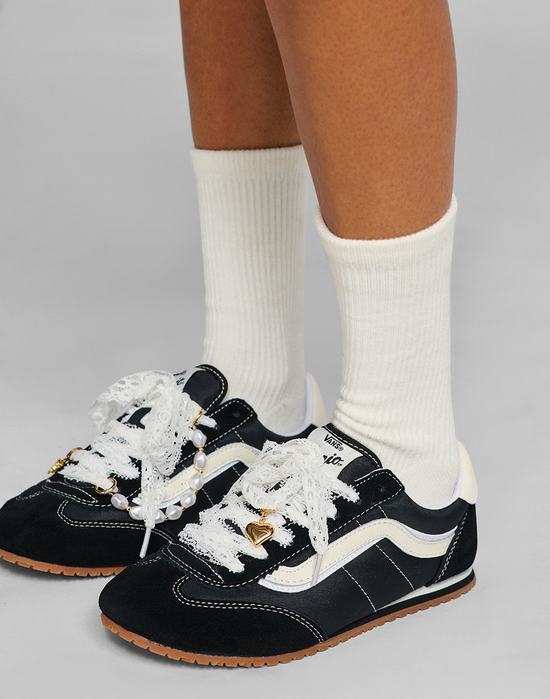 Close-up of gold shoe charms on black and white Super Lowpro shoes in a photography studio.