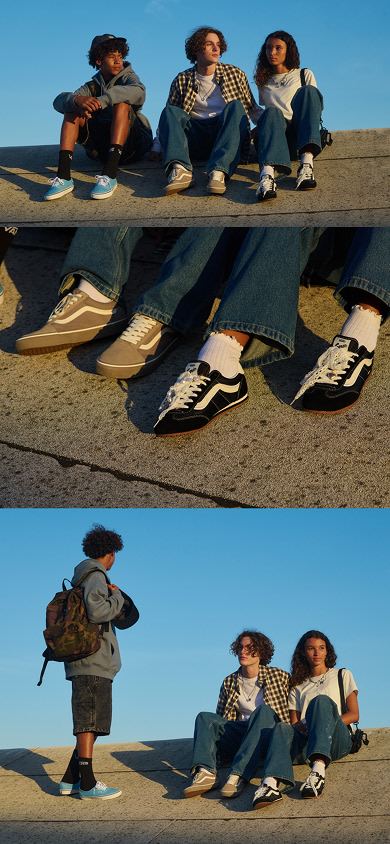 A man sits on a curb wearing Racing Red Super Lowpro shoes and Vans clothes.