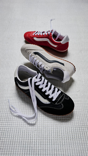 Three Super Lowpro shoes rest on the floor in Racing Red, Marshmallow White, and Black.