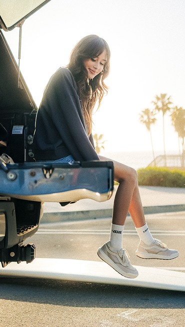 Vans Surfer Maddie Miller sits on the gate of a pickup truck at the beach wearing a pair of Vintage White UltraRange 2.0 on a sunny day.