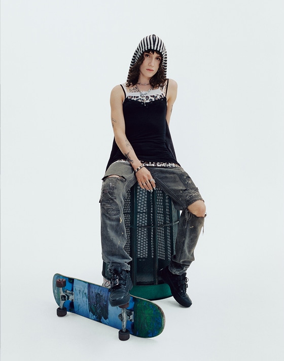 Vans Skater Efron Danzig poses in a photography studio on a trash can with a skateboard wearing her Premium Old Skool.