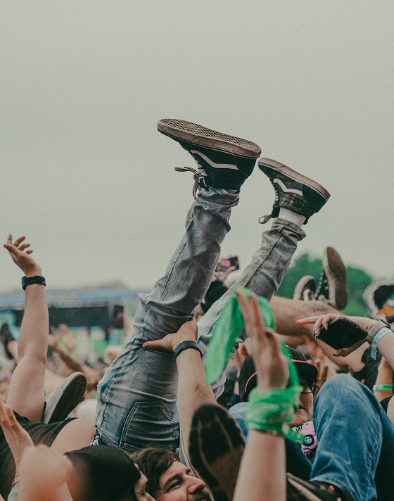 A person crowd surfs with their legs straight in the air wearing black and white Sk8-Hi at Warped Tour.