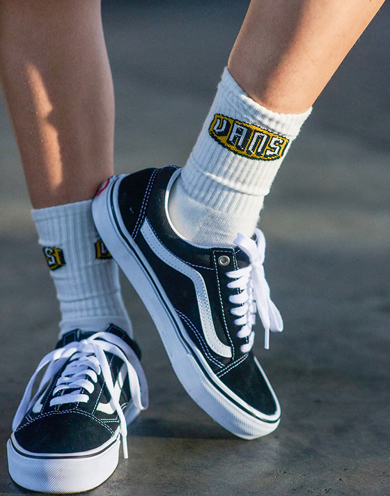 A pair of grey mint green Knu Skool hang from a nail by their laces in the afternoon sun.