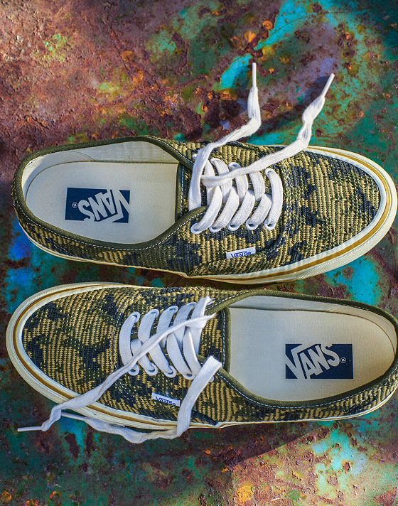 A pair of antique gold and green Premium Authentic rest on top of a rusty oil drum in a warehouse.
