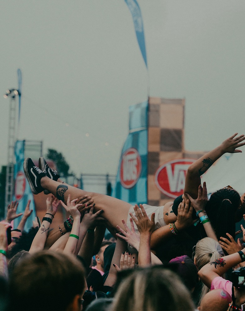 A person crowd surfs with their legs straight in the air wearing black and white Sk8-Hi at Warped Tour.