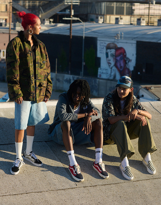 Three teenagers hang out on a roof wearing Old Skool, Checkerboard Classic Slip-On, and Vans clothes.
