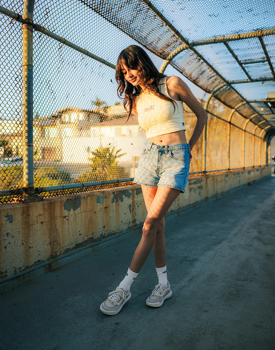Vans Surf Team Rider Maddie Miller poses on a pedestrian bridge wearing the Everydayness Crop Tank Top and vintage white UltraRange 2.0.