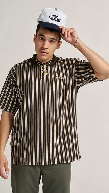 A man poses in a photography studio wearing a black and white striped shirt.