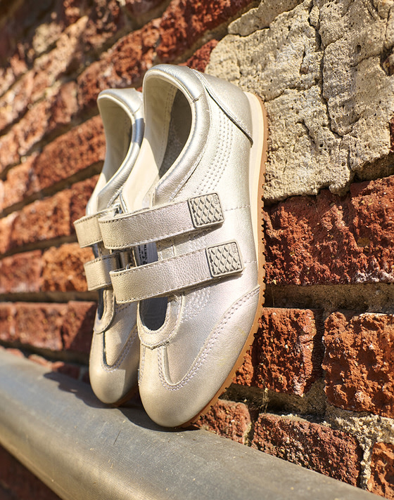 A pair of silver Super Lowpro lean up against a brick wall.