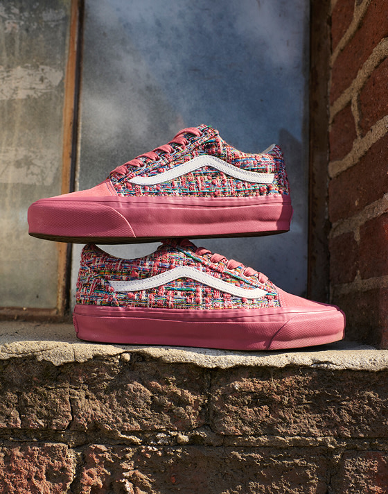 A pair of vibrant pink engineered knit Premium Old Skool are stacked on one another on a loading dock next to a brick wall.
