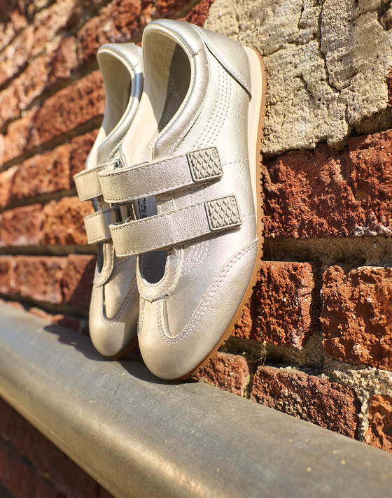 A pair of silver Super Lowpro lean up against a brick wall.