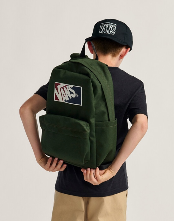 Close-up of a kid adjusting the dried kelp green Kids Old Skool Grom Backpack in a photography studio.