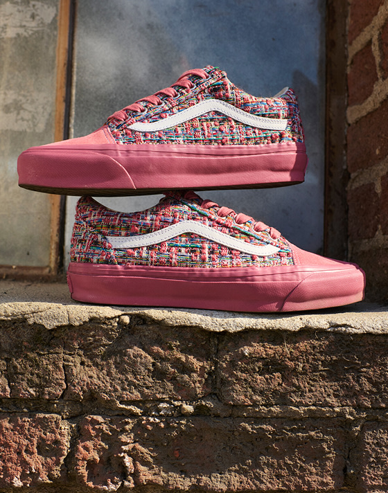A pair of vibrant pink engineered knit Premium Old Skool are stacked on one another on a loading dock next to a brick wall.