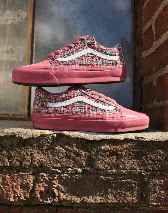 A pair of vibrant pink engineered knit Premium Old Skool are stacked on one another on a loading dock next to a brick wall.