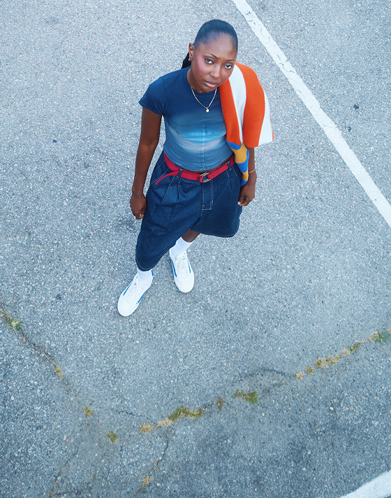 An overhead shot of musician Vanessa in a parking lot wearing denim shorts and white Super Lowpro on the set of Open Set Los Angeles.