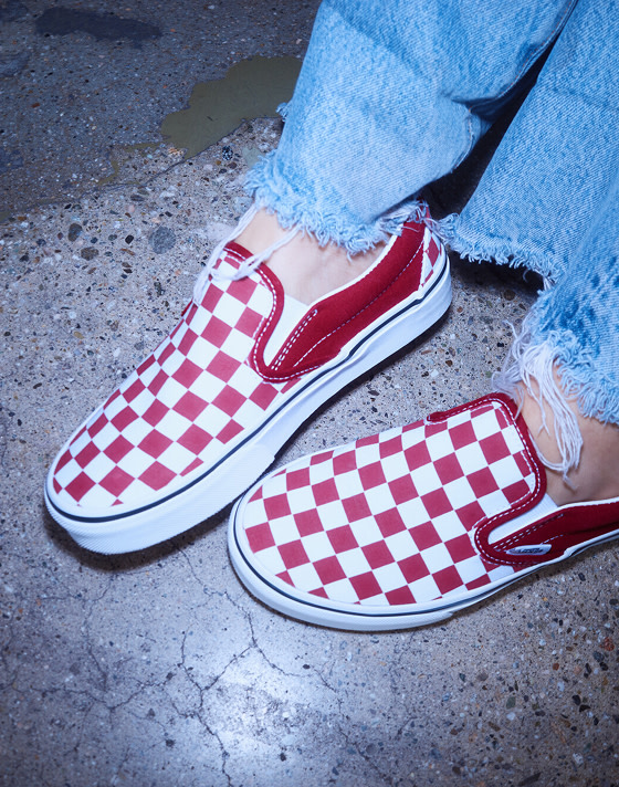 A close-up of model Beanie wearing red Checkerboard Classic Slip-On on concrete on the set of Open Set Los Angeles.