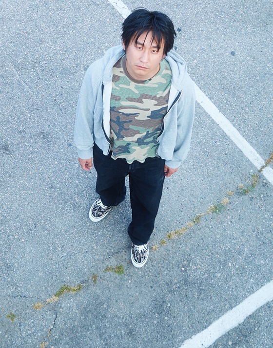 An overhead shot of skater Masa in a parking lot wearing Leopard Brown Premium Authentic with a camo shirt on the set of Open Set Los Angeles.