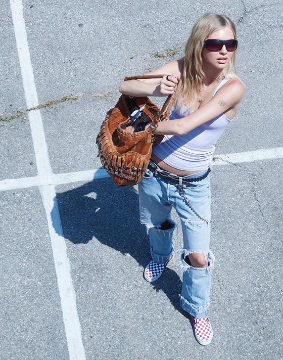 An overhead shot of model Beanie in a parking lot wearing ripped jeans and red Checkerboard Classic Slip-On on the set of Open Set Los Angeles.