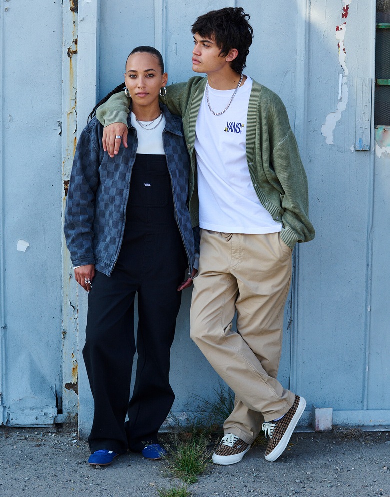 A young man wearing a moss green cardigan and a woman wearing a white hoodie smile for the camera.